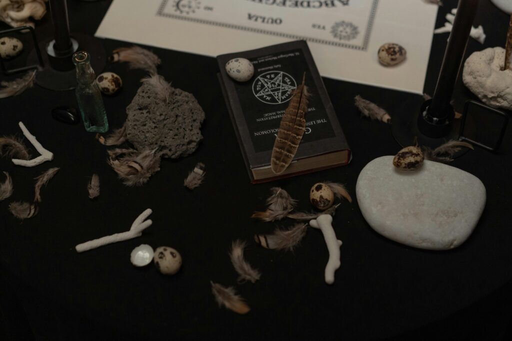 Black Magic Specialist A dark, mysterious scene with a book, feathers, stones, and ritualistic items.